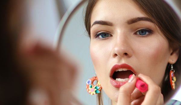Junge Frau beim Auftragen von Make-up vor dem Spiegel — Einsteiger-Fernlehrgang Make-up
